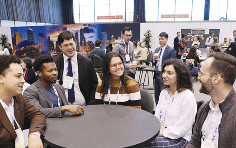 A group of professionally dressed men and women of various ethnicities sit around a small table at the RSNA annual meeting